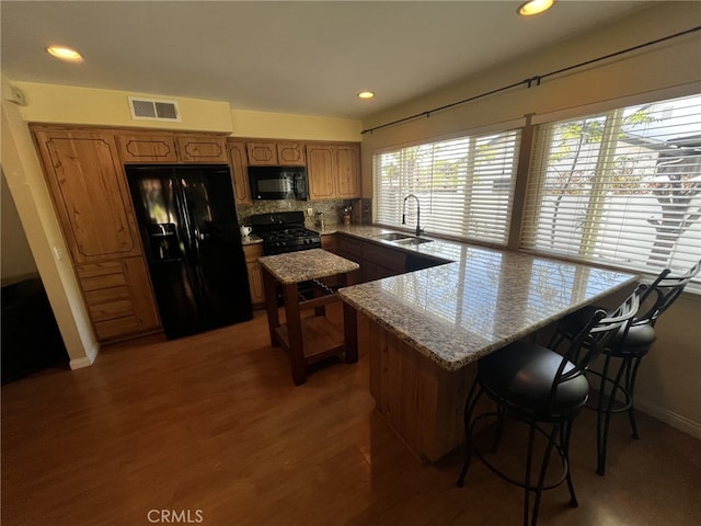 kitchen featuring a peninsula, visible vents, a wealth of natural light, and black appliances