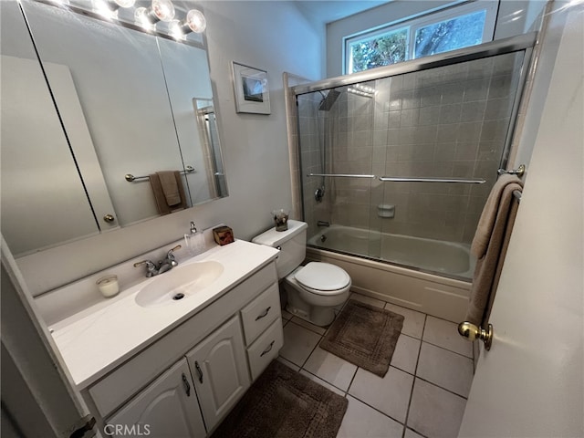 bathroom with vanity, tile patterned flooring, combined bath / shower with glass door, and toilet