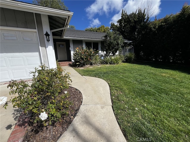 entrance to property with board and batten siding, an attached garage, and a yard