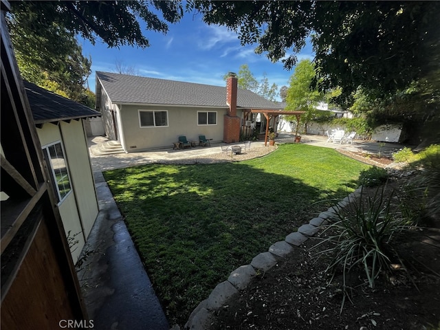 back of property with a lawn, a patio, a chimney, and stucco siding