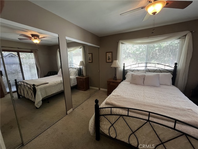 bedroom featuring carpet floors, multiple closets, ceiling fan, and baseboards