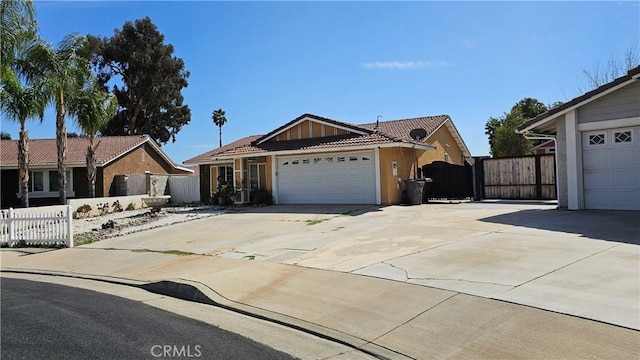 single story home with a tile roof, concrete driveway, fence, a gate, and a garage