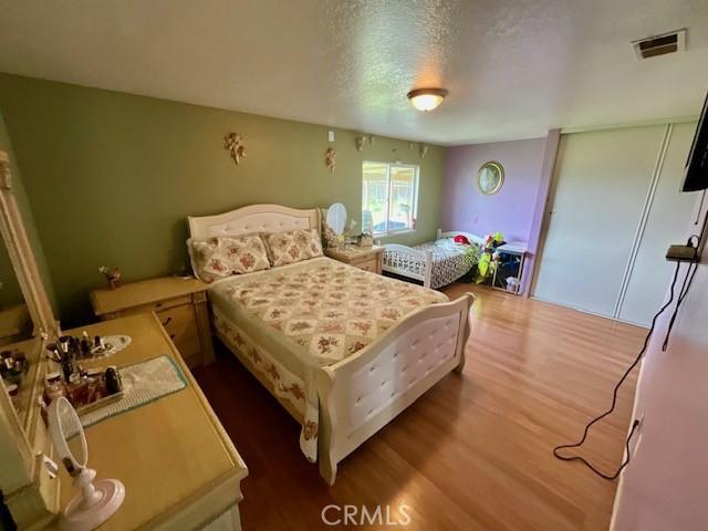 bedroom featuring visible vents, wood finished floors, and a textured ceiling