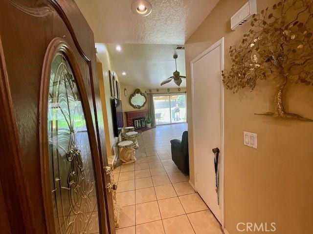 hallway featuring a textured ceiling, vaulted ceiling, recessed lighting, and light tile patterned floors