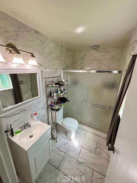 full bath featuring tile walls, marble finish floor, toilet, vanity, and a stall shower
