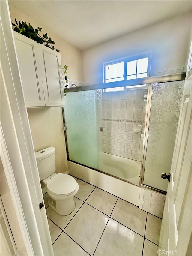 bathroom with enclosed tub / shower combo, toilet, and tile patterned flooring