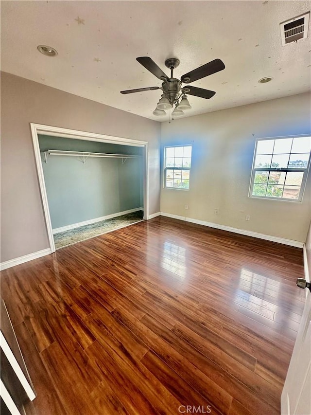 unfurnished bedroom featuring a closet, visible vents, wood finished floors, and baseboards