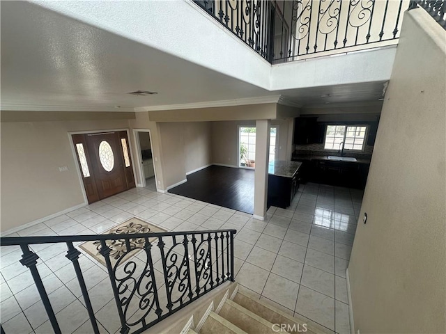 entrance foyer featuring baseboards, visible vents, light tile patterned floors, and crown molding