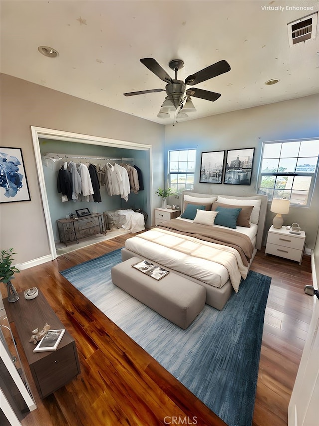 bedroom with a closet, a ceiling fan, visible vents, baseboards, and wood finished floors