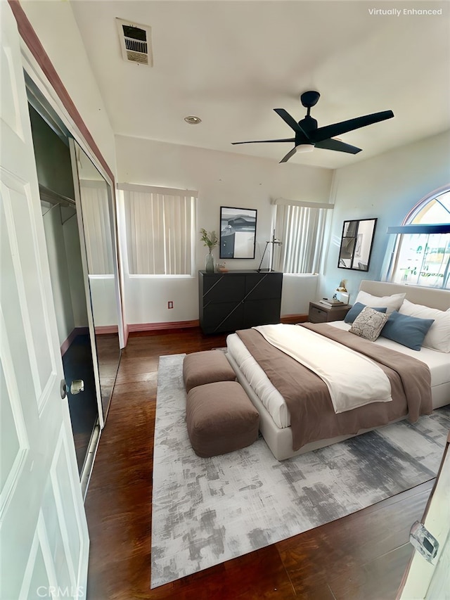 bedroom with wood finished floors, visible vents, a ceiling fan, and a closet