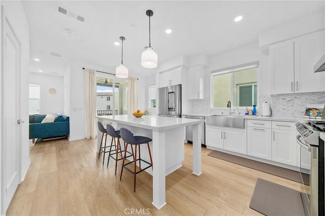 kitchen with a sink, decorative backsplash, visible vents, and appliances with stainless steel finishes