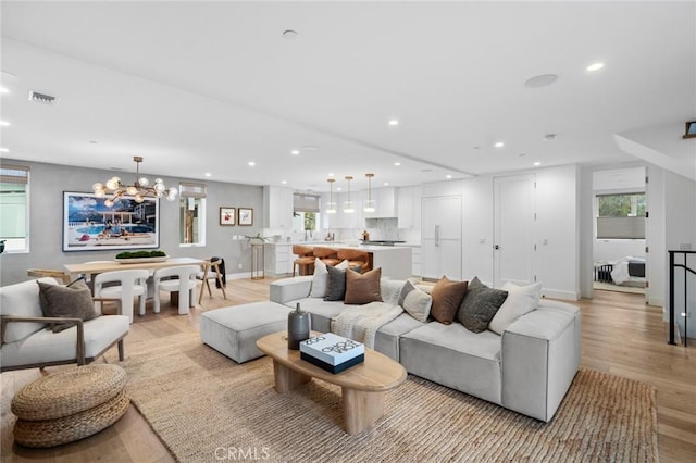 living room featuring a wealth of natural light, light wood-style floors, an inviting chandelier, and recessed lighting
