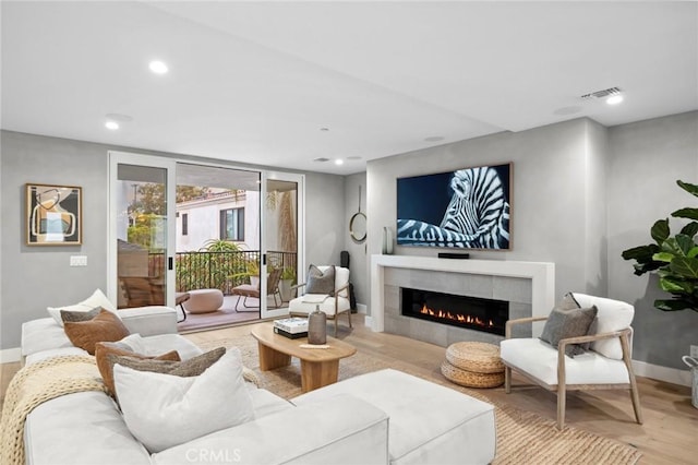 living room with wood finished floors, a fireplace, visible vents, baseboards, and recessed lighting