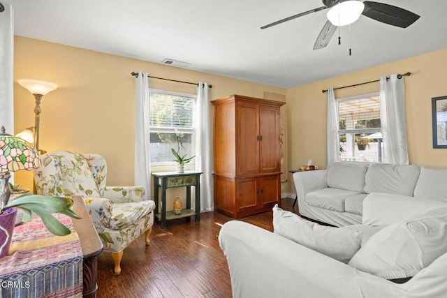 living area featuring plenty of natural light, ceiling fan, and dark wood-type flooring