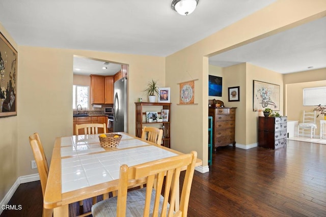 dining space featuring baseboards and dark wood finished floors