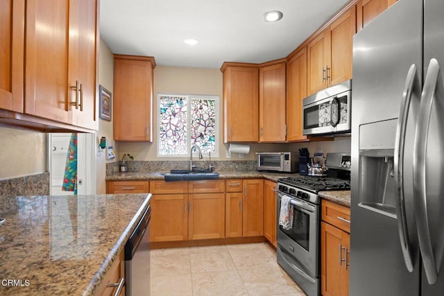 kitchen with a sink, stainless steel appliances, a toaster, and brown cabinets