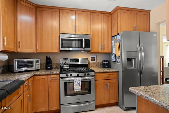 kitchen with brown cabinets, a toaster, and appliances with stainless steel finishes