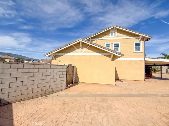 rear view of house with a gate, fence, stucco siding, driveway, and a patio area
