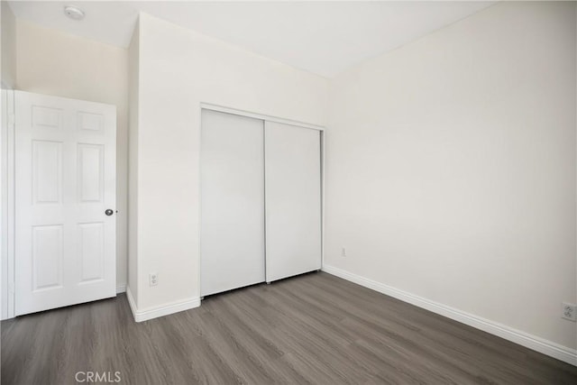 unfurnished bedroom with baseboards, a closet, and wood finished floors