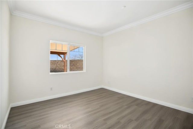 spare room with dark wood-style flooring, ornamental molding, and baseboards