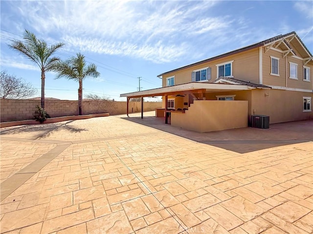 rear view of house with central AC, a fenced backyard, stucco siding, and a patio area