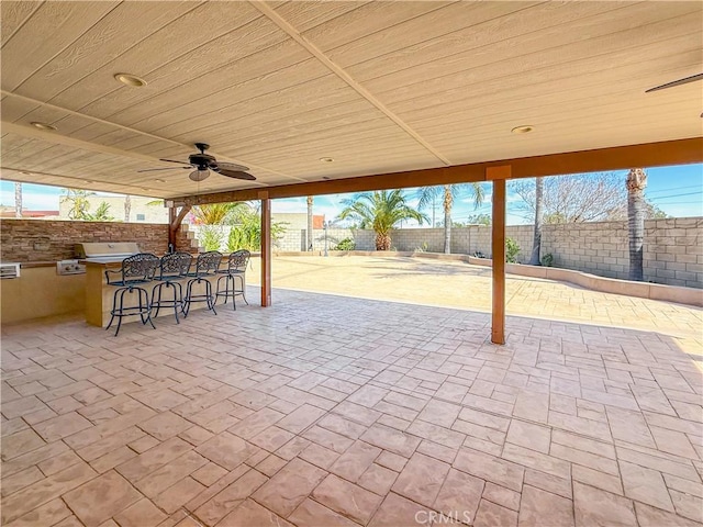 view of patio featuring a grill, exterior kitchen, a fenced backyard, and ceiling fan