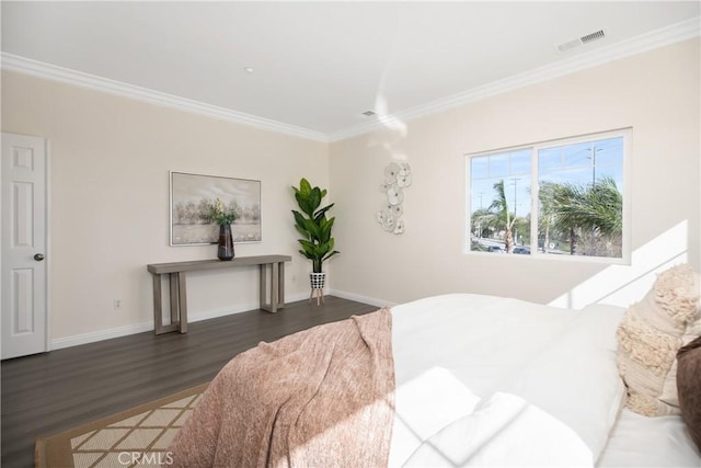 bedroom featuring baseboards, visible vents, crown molding, and wood finished floors