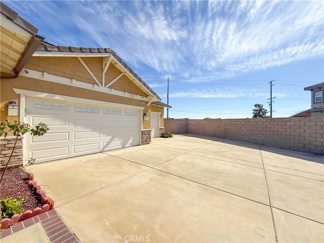 garage featuring fence and concrete driveway