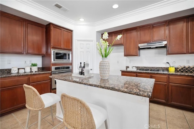 kitchen with light tile patterned floors, ornamental molding, under cabinet range hood, visible vents, and appliances with stainless steel finishes