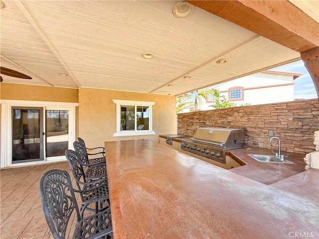 view of patio with exterior kitchen, a sink, fence, and grilling area