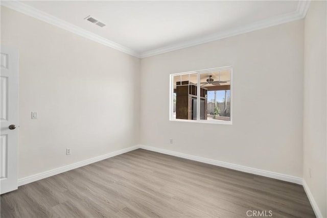 spare room with baseboards, ornamental molding, visible vents, and wood finished floors