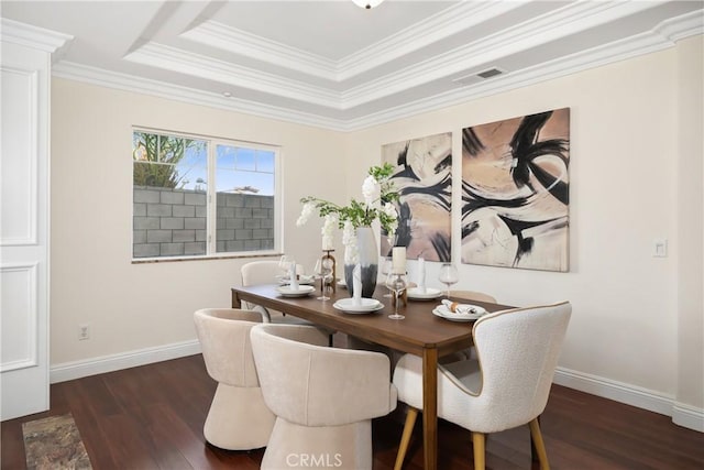 dining room featuring a tray ceiling, wood finished floors, baseboards, visible vents, and ornamental molding