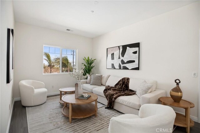living room with baseboards, visible vents, and wood finished floors