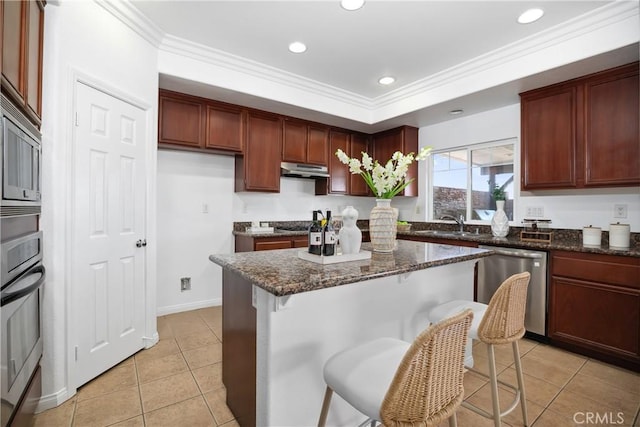 kitchen featuring crown molding, dark stone counters, a kitchen island, light tile patterned flooring, and appliances with stainless steel finishes