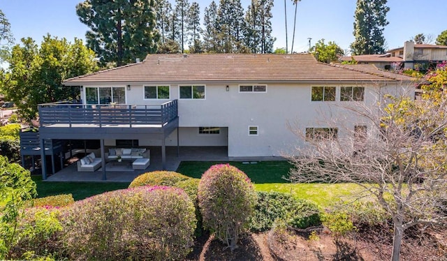 rear view of house featuring an outdoor living space, a lawn, a wooden deck, a patio area, and stucco siding
