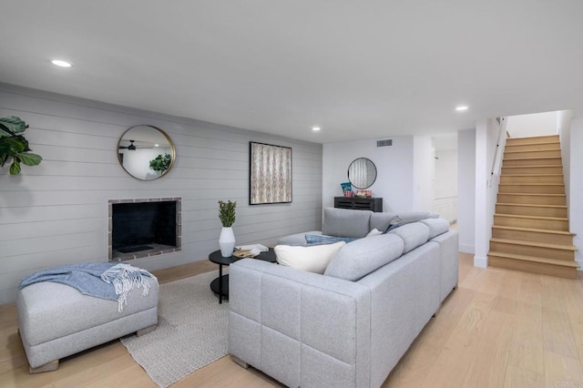 living room featuring recessed lighting, light wood-style flooring, stairway, and a fireplace