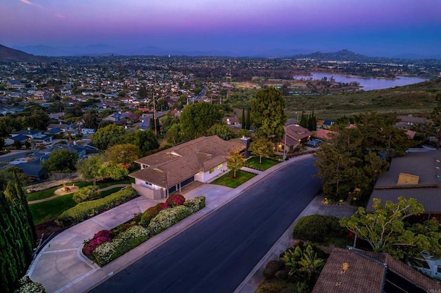 aerial view at dusk with a water view and a residential view