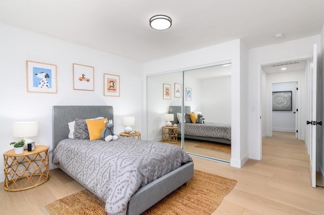 bedroom with light wood-style floors, baseboards, and a closet