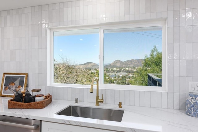 kitchen featuring a sink, light stone countertops, a mountain view, and dishwasher