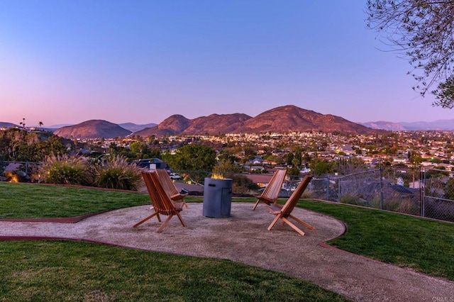 playground at dusk with a yard, fence, and a mountain view
