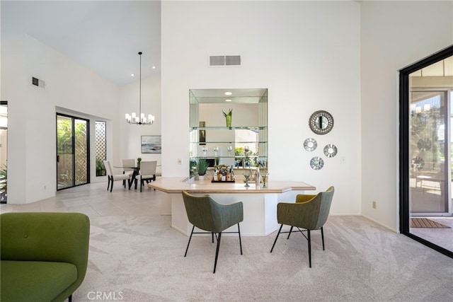 dining space with visible vents, light carpet, a towering ceiling, and a chandelier