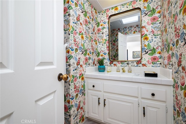 bathroom with wallpapered walls and vanity