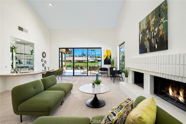carpeted living room featuring a fireplace, visible vents, high vaulted ceiling, and recessed lighting