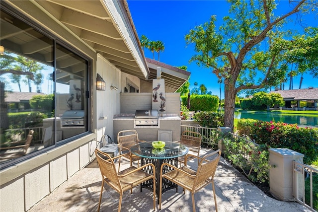 view of patio / terrace featuring a grill, outdoor dining area, area for grilling, and a water view