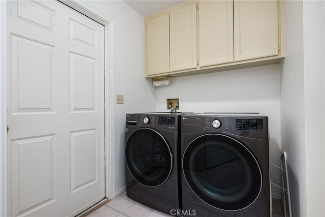 clothes washing area featuring washer and dryer, light tile patterned floors, and cabinet space