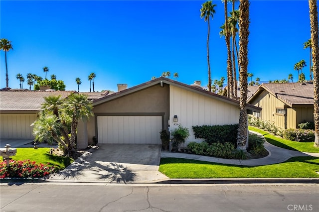 mid-century home with stucco siding, an attached garage, and concrete driveway