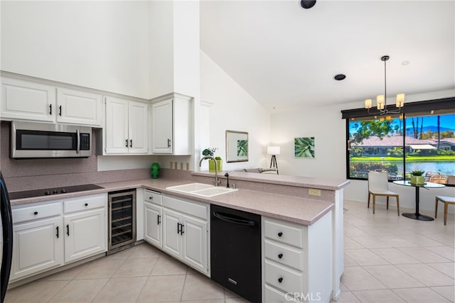 kitchen with a sink, black appliances, light tile patterned flooring, a peninsula, and wine cooler