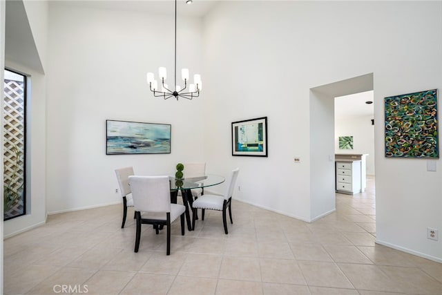dining room with light tile patterned flooring, a towering ceiling, baseboards, and an inviting chandelier