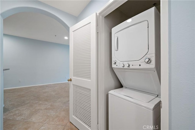 laundry room with arched walkways, baseboards, recessed lighting, stacked washing maching and dryer, and laundry area