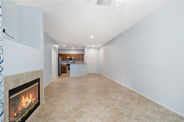 unfurnished living room with recessed lighting, visible vents, arched walkways, baseboards, and a fireplace